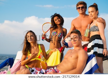 Group of multi ethnic friends with drinks relaxing on a beach