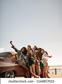 Group Of Multi Ethnic People Taking A Selfie Near The Car. Young Men And Women Together On Road Trip Making Selfie.