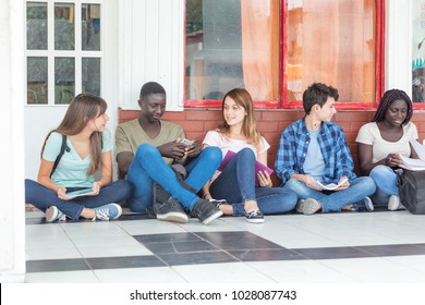 Group Of Multi Ethnic Teenagers At School Talking Seated On The Floor.