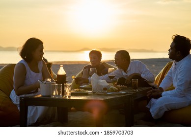 Group Of Multi Generation Asian Family Enjoy Dinner Party On The Beach At Sunset. Diverse Family With Child Girl, Adult And Senior Couple Relax And Having Fun Together On Summer Holiday Vacation