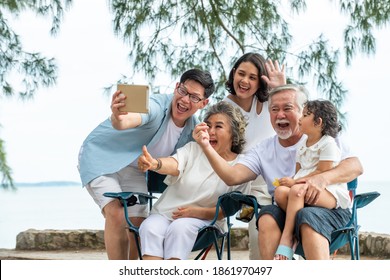 Group of Multi generation Asian family using digital tablet video call with their family friend on the beach in summer day. Happy big family enjoy and having fun together in summer holiday vacation - Shutterstock ID 1861970497