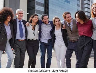 Group Of Multi Generational Business People Hugging Each Other Outside Of Office Building