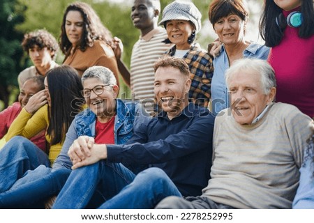 Group of multi generational people having fun together outdoor - Multiracial friends enjoy day at city park