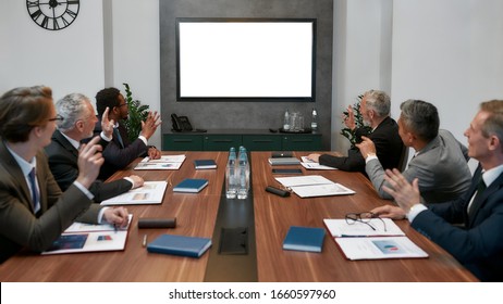 Group Of Multicultural Business People Having Video Conference While Sitting In The Meeting Room. Business Team Looking At Screen And Waving. Skype Call. Teamwork. Office Life