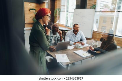 Group of multicultural businesspeople having a discussion during a boardroom meeting. Team of diverse business professionals sharing creative ideas in an inclusive workplace. - Powered by Shutterstock