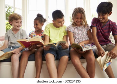 Group Of Multi-Cultural Children Reading On Window Seat