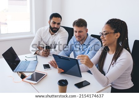 Group of multicultural employees discussing paper notes while analyzing report statistics on briefing meeting in office interior, young colleagues talking about trade exchange and CEO profession