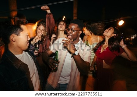 A group of multicultural friends is having a good time, dancing and drinking beer at the music festival at night. Stock photo © 