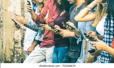Group of multicultural friends using smartphone outdoors - People hands addicted by mobile smart phone - Technology concept with connected men and women - Shallow depth of field on vintage filter tone - Shutterstock ID 751028674