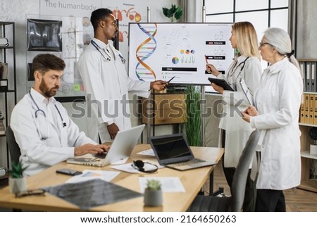 Group of multicultural medical workers discussing gene modification while gathering at hospital meeting room. Qualified doctors researching dna peculiarities during international conference.