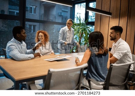 Group of multicultural professionals engaged in teamwork and discussion at a modern office, sharing ideas and planning projects together