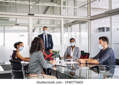 Group of multiethnic business people in meeting wearing face mask in conference room during covid19 pandemic. Business workers discussing strategy while wearing masks and keeping social distancing.