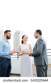 Group Of Multiethnic Business People Talking To Each Other And Smiling While Standing Outdoor In An Urban Setting