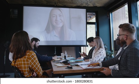 Group Of Multiethnic Business People Using Projector For Online Web Conference Call With Female Coach At Modern Office.