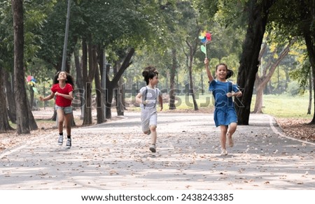 Group multiethnic children enjoy weekend outdoors activities together running with pinwheels in hands laughing, school kids carefree days lifestyle share happy moments pure zest childhood merriment