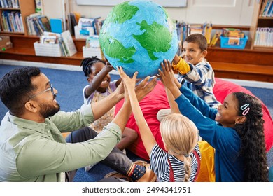 Group of multiethnic children with male teacher holding model of earth in classroom. High angle view of geography teacher with schoolgirls and schoolboys holding a big handmade earth model. - Powered by Shutterstock