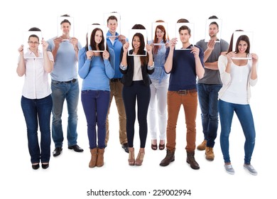 Group Of Multiethnic College Students Holding Photographs In Front Of Faces Against White Background