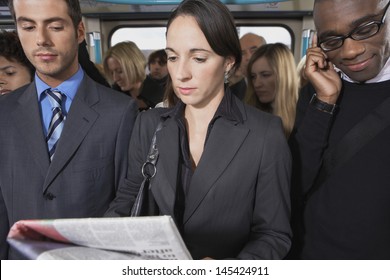 Group of multiethnic commuters in a train with woman reading newspaper - Powered by Shutterstock