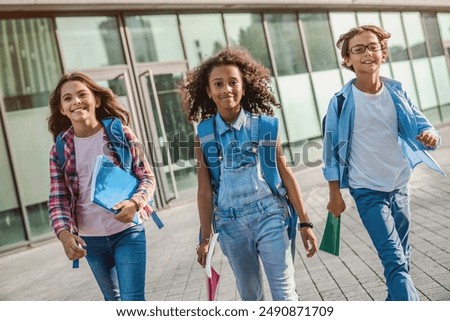 Group of multiethnic elementary middle school kids children pupils classmates walking after school outdoor running out outside at the end of the lessons. Finish welcome back school concept.