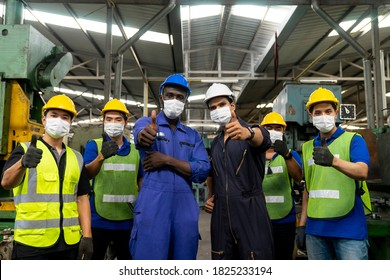 Group Of Multiethnic Engineer With Workers Giving Thumbs Up And Wearing Surgical Mask To Prevent Covid-19 In Manufacturing Factory. Successful Diverse Teamwork Standing In Workplace.