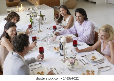Group of multiethnic friends drinking and socialising at dinner party