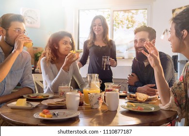 A group of multi-ethnic friends gathered around a table in the kitchen for breakfast - Powered by Shutterstock