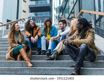 Group Of Multiethnic Friends Laughs And Jokes On The Stairs In The City. Return To Normal Life