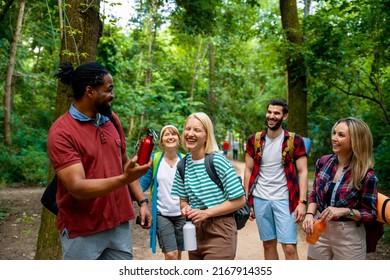 Group Of Multiethnic Friends On Hiking Or Trekking In Green Forest Trail. Happy Young Diverse People Walking In Woods