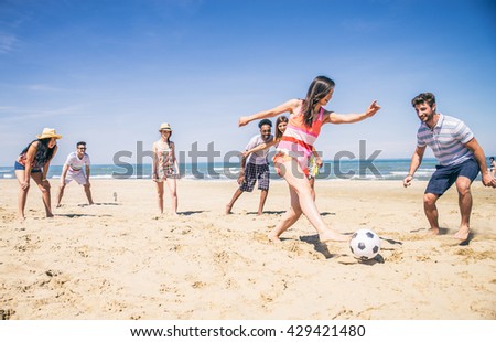 Group of multiethnic friends playing soccer on the beach - Football match on the sand on summertime - Tourists having fun on vacation with beach games