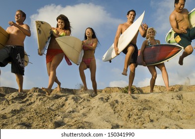 Group of multiethnic friends with surfboards running on sandy beach - Powered by Shutterstock