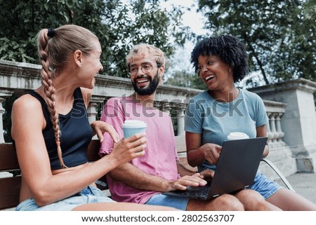 group of multiethnic friends using laptop and having fun on city street in Europe at summer season 