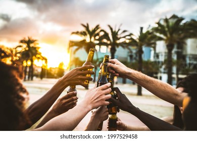 Group of multiethnic happy friends having party outside celebrating toasting beer bottles on sunset - Young people hanging out drinking alcohol together - Celebration and happiness concept - Powered by Shutterstock