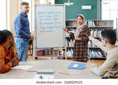 Group of multi-ethnic immigrant students learning English language at school doing task with irregular verbs together - Shutterstock ID 2160229125