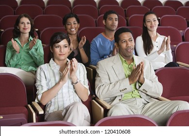 Group of multiethnic people applauding at a performance while sitting in auditorium