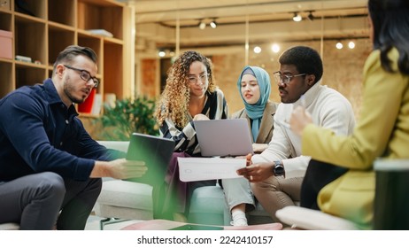 A Group of Multiethnic People Brainstorming Using Laptop and Charts in a Meeting Room at Office. Enthusiastic Young Adults Analyzing New Data To Improve Startup Performance. Medium Shot - Powered by Shutterstock