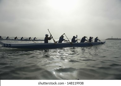Group of multiethnic people paddling outrigger canoes in race