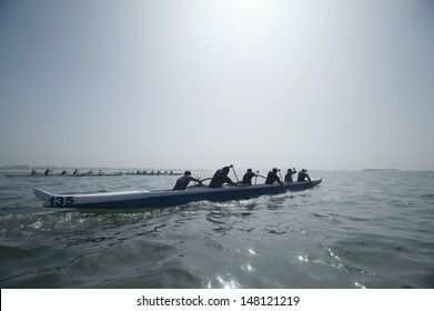 Group of multiethnic people paddling outrigger canoes in race
