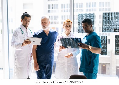 Group of multi-ethnic professional doctors are discussing together history disease of patient using MRI scan of head and digital tablet during medical conference. Concept of medicine and health care. - Powered by Shutterstock