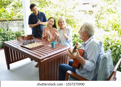 a group of multiethnic senior people playing guitar and sing a song after playing chess board with happy smiling face on sunny day - Powered by Shutterstock