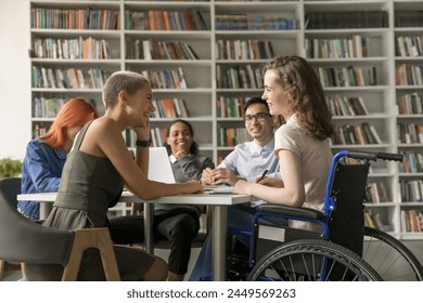 Group of multi-ethnic students and girl with disability engaged in teamwork in high-school library, gathered together for exams preparation, having warm friendly relations. Friendship, communication - Powered by Shutterstock