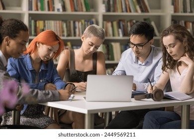 Group of multiethnic students sit at desk in library, jotting notes, writing in copybook, make assignment or essay, engaged in studies and personal development during lecture or educational seminar - Powered by Shutterstock