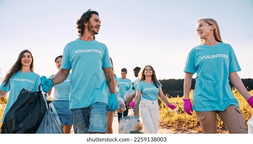 A group of multiethnic volunteers walking with garbage bags after trash, waste collecting. Happy and tired activists talking, high five. Friendship, volunteering, teamwork concept. - Powered by Shutterstock