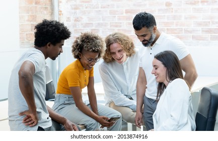Group of multiethnic workers looking at the mobile in group and smiling in a coworking. Startup.