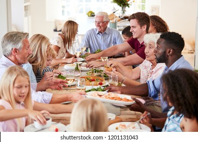 Group Of Multi-Generation Family And Friends Sitting Around Table And Enjoying Meal