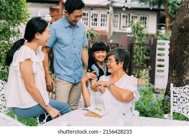 Group of multi-generational Asian family enjoying a good time together in backyard garden and smiling with happiness - Powered by Shutterstock