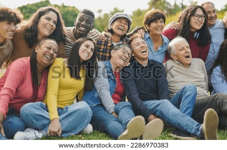 Group of multigenerational people having fun together outdoor - Multiracial friends enjoy day at city park
