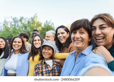 Group of multigenerational people taking selfie with phone camera - Multiracial friends of different ages having fun together - Main focus on two right women faces - Powered by Shutterstock