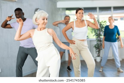 Group of multinational sports aged people rehearsing modern dance in dance hall - Powered by Shutterstock