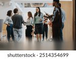 A group of multiracial colleagues engaging in a casual conversation in a brightly lit modern office space, exemplifying teamwork and networking.