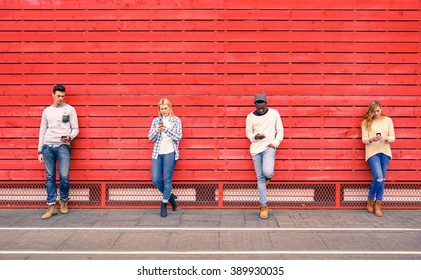 Group of multiracial fashion friends using smartphone with red wood background - Technology addiction in urban lifestyle with disinterest towards each other - Addicted people to modern mobile phones